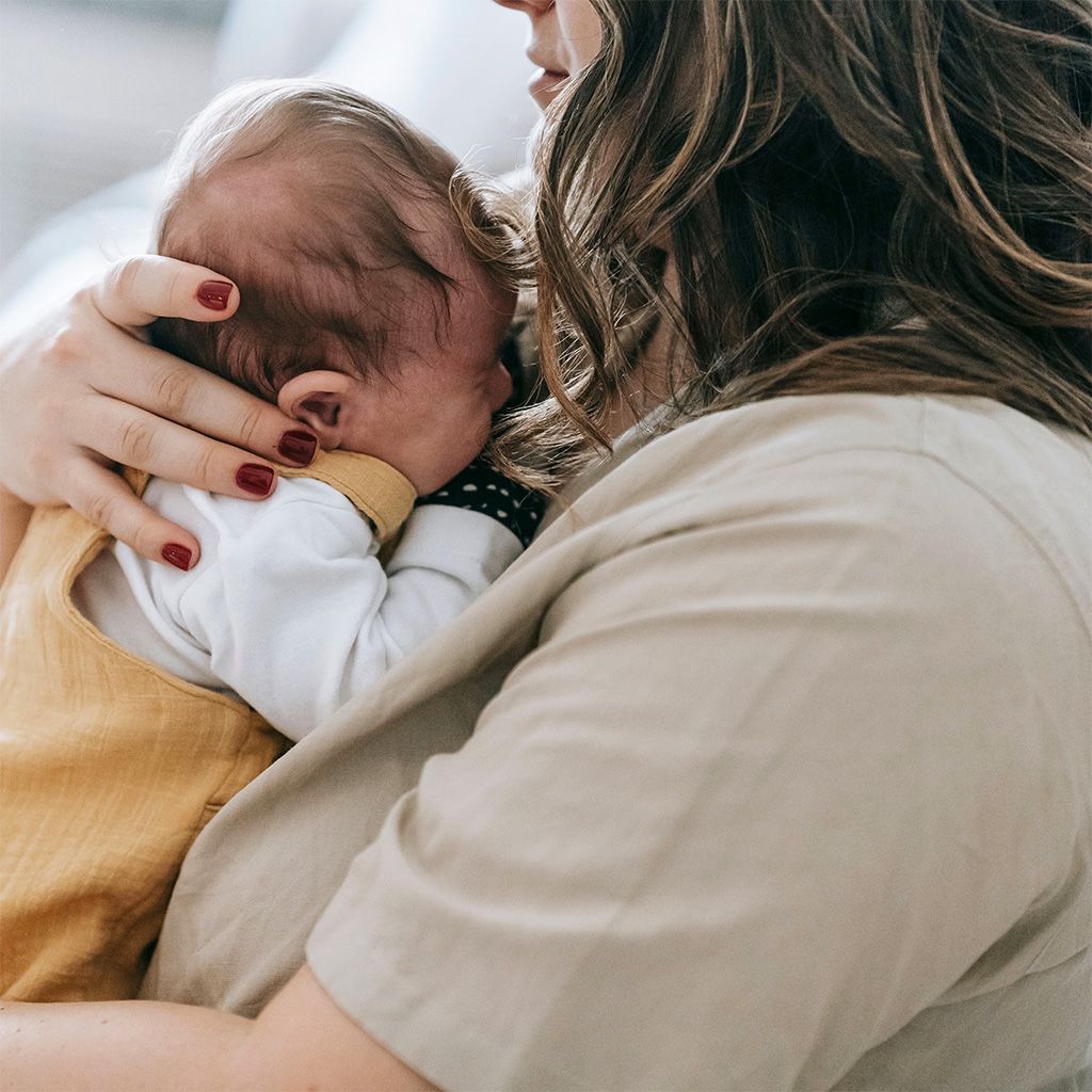 A mum holds a crying newborn baby to her chest